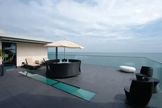 Pohled na moře přes střešn&iacute; terasu s lounge n&aacute;bytkem